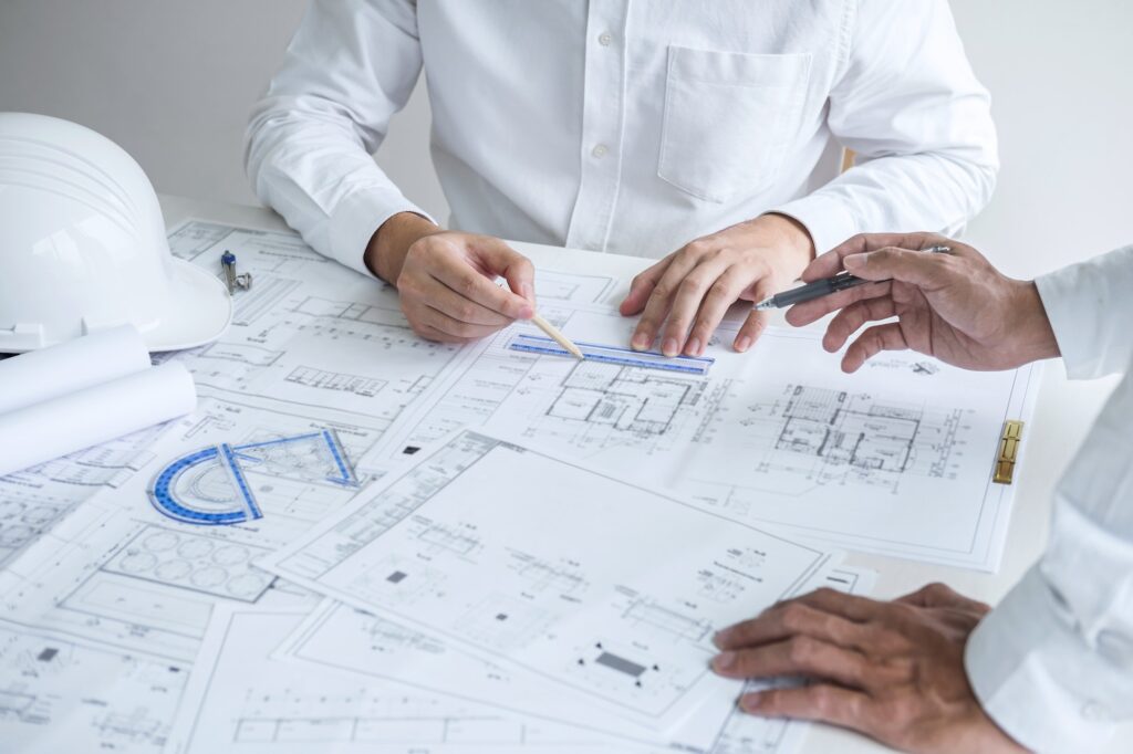 Construction engineering or architect discussing a blueprint and building model while checking