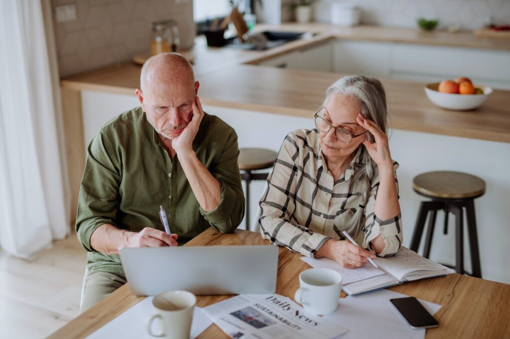 Stressed senior couple calculate expenses or planning budget together at home.