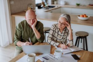 Stressed senior couple calculate expenses or planning budget together at home.